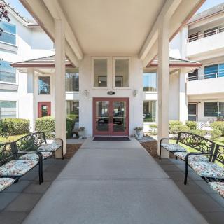 A welcoming building entrance with benches and decorative landscaping.