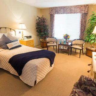 A cozy and well-decorated bedroom with a comfortable bed, chairs, and decorative plants.