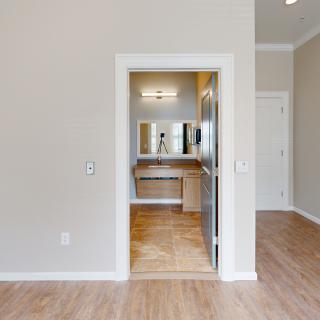 A modern, minimalist bathroom view with wooden flooring and a large mirror above the sink.