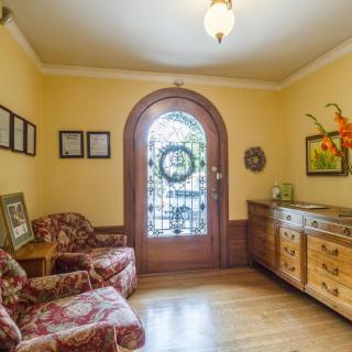 A cozy living room with traditional decor, featuring patterned armchairs, a wooden floor, and a decorative arched door.