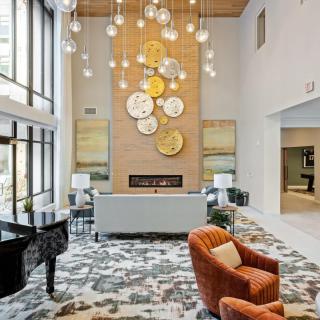 A modern lobby featuring a stylish chandelier, grand piano, and contemporary art decor.