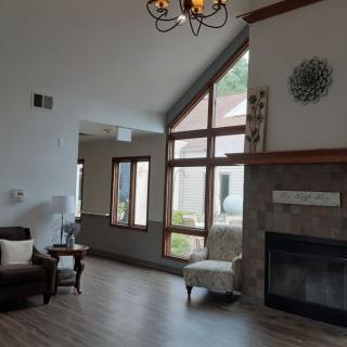 A cozy living room with a fireplace, large windows, and comfortable seating.