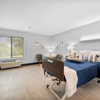 A well-lit hospital room featuring a single bed, comfortable seating, and modern decor.