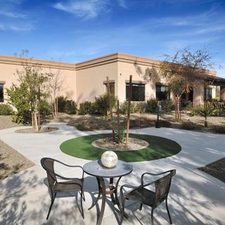 A sunny courtyard with chairs and a table surrounded by desert landscaping.