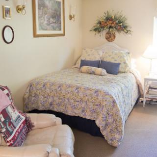 A cozy bedroom featuring a neatly made bed with floral bedding and soft lighting.