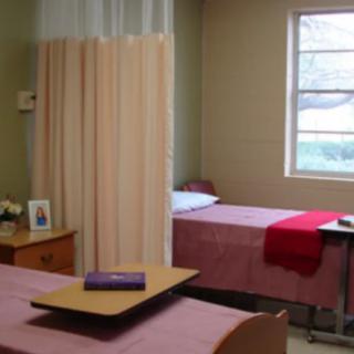 A hospital room with two patient beds separated by a curtain divider.