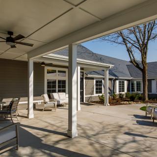 A modern residential patio with comfortable outdoor seating under a covered area.