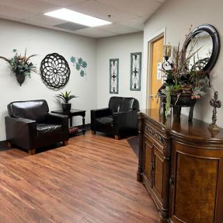 A well-decorated waiting room featuring black leather chairs and wooden accents.