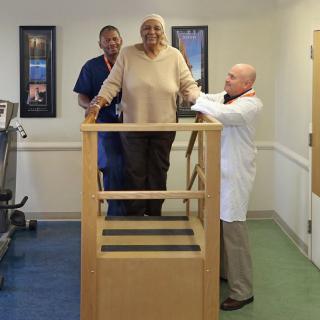 Healthcare professionals assist a patient with physical therapy exercises.