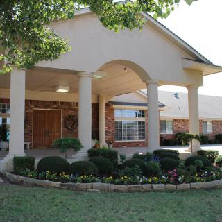 A residential building with a landscaped entrance and columned porch.