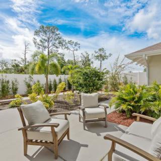 A sunny backyard patio with comfortable seating and lush garden surroundings.