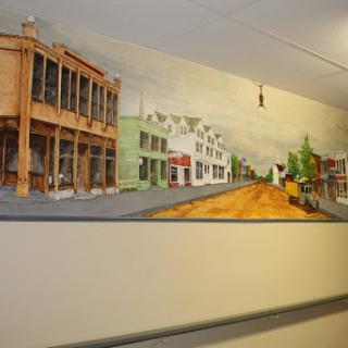A vibrant mural depicting a streetscape with various buildings and greenery.