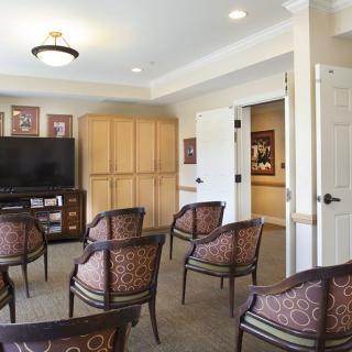 A small meeting room setup with several chairs arranged in front of a television.