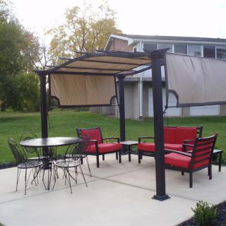 Outdoor patio area with a pergola, red-cushioned seating, and a round table with chairs.