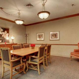 A conference room with a large wooden table, surrounded by chairs, and lit by chandeliers.