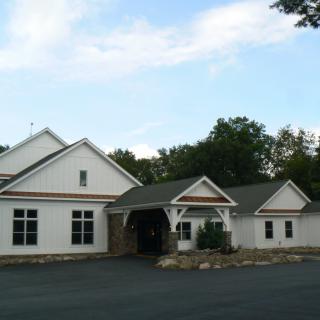 A white residential building with a gabled roof surrounded by trees.