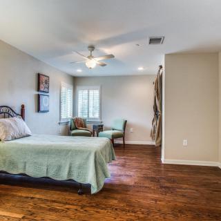 A spacious bedroom with wooden flooring, a bed, and cozy seating area.