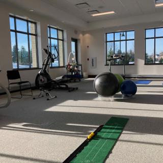 A well-lit gym space featuring various workout equipment and exercise balls.
