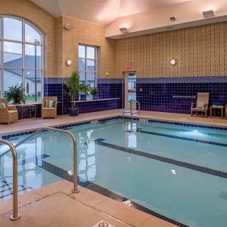 A serene indoor swimming pool area with elegant seating and large windows.