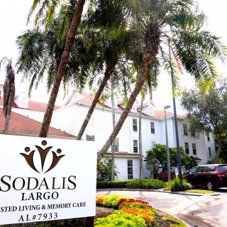 A view of the Sodalis Largo Assisted Living and Memory Care facility surrounded by palm trees.