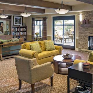 A cozy living room with comfortable seating, a fireplace, and a view of an outdoor patio.