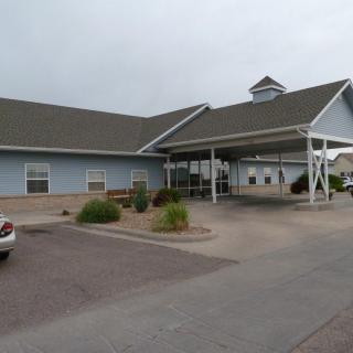 A single-story building with a carport and surrounding landscaping.