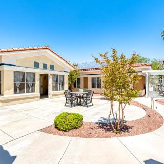 A sunny backyard with a patio and outdoor seating surrounded by simple landscaping.