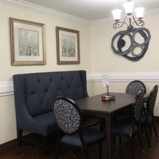 A cozy dining room with a tufted booth, elegant chairs, and modern wall art.