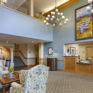 A spacious lobby interior with a seating area, decorative chandelier, and reception desk.