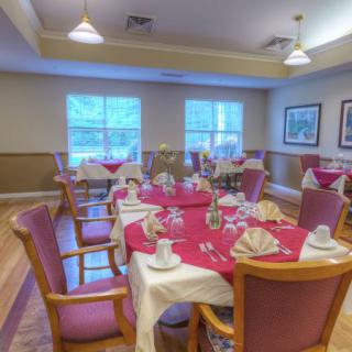 A well-arranged dining room with tables set for a meal, featuring red tablecloths and neatly folded napkins.