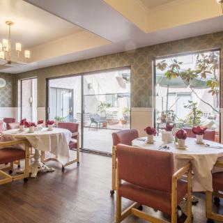 A well-lit dining room with elegantly set tables and large windows.