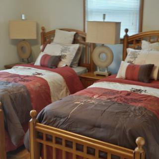 A cozy bedroom with two twin beds featuring colorful bedding and matching lamps.
