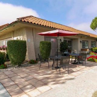A sunny patio with outdoor seating and an umbrella beside a building.