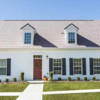 A charming suburban house with a red door and dormer windows.