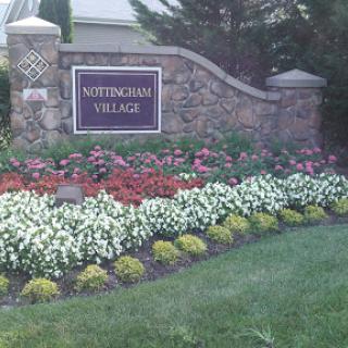 A beautifully arranged floral landscape at the entrance of a community named 'Nottingham Village'.
