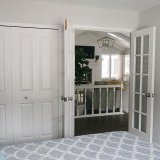 A modern bedroom with French doors leading to a well-lit hallway.