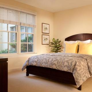 A cozy bedroom with a neatly made bed, large window, and decorative elements.