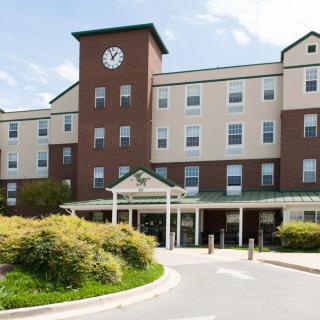 A multi-story building with a clock tower and landscaped entrance.