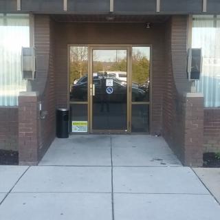 A building entrance with glass doors and brick walls.