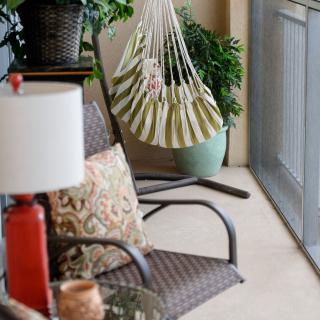 A cozy patio setting with wicker chairs, a hammock, and potted plants.