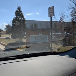 View from inside a vehicle showing a parking area and nearby building.