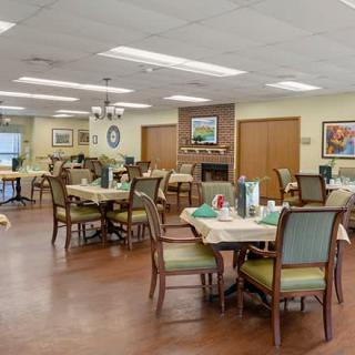 A well-lit dining area with neatly arranged tables and chairs, featuring elegant decor.
