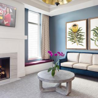 A modern living room featuring a sofa, coffee table, fireplace, and elegant artwork.