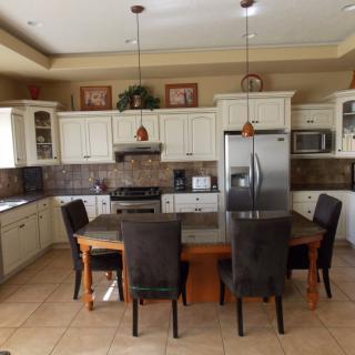 A modern kitchen with stainless steel appliances, a dining table, and tiled flooring.