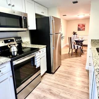 A modern kitchen featuring stainless steel appliances and granite countertops, leading to a cozy dining area.