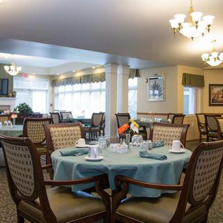An elegantly set dining room with multiple tables and chairs, featuring tasteful decor and lighting.