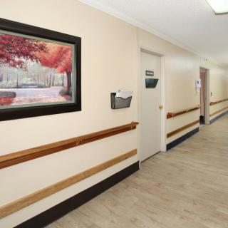 A brightly lit hallway with a door and a painting on the wall.