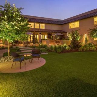 A beautifully landscaped backyard at dusk with patio furniture and ambient lighting.