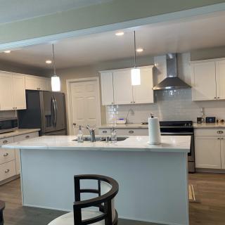 A modern kitchen with a central island, white cabinets, and stainless steel appliances.