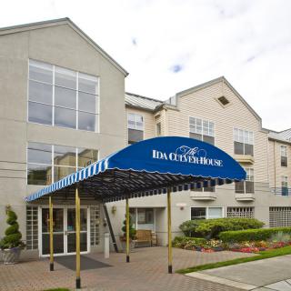 The entrance of a hotel with a blue awning and modern architecture.